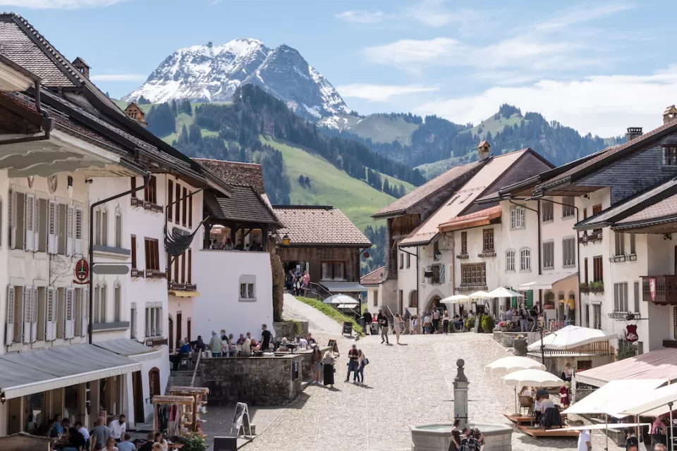 View of pedestrian plaza in Swiss village with Alps in background.